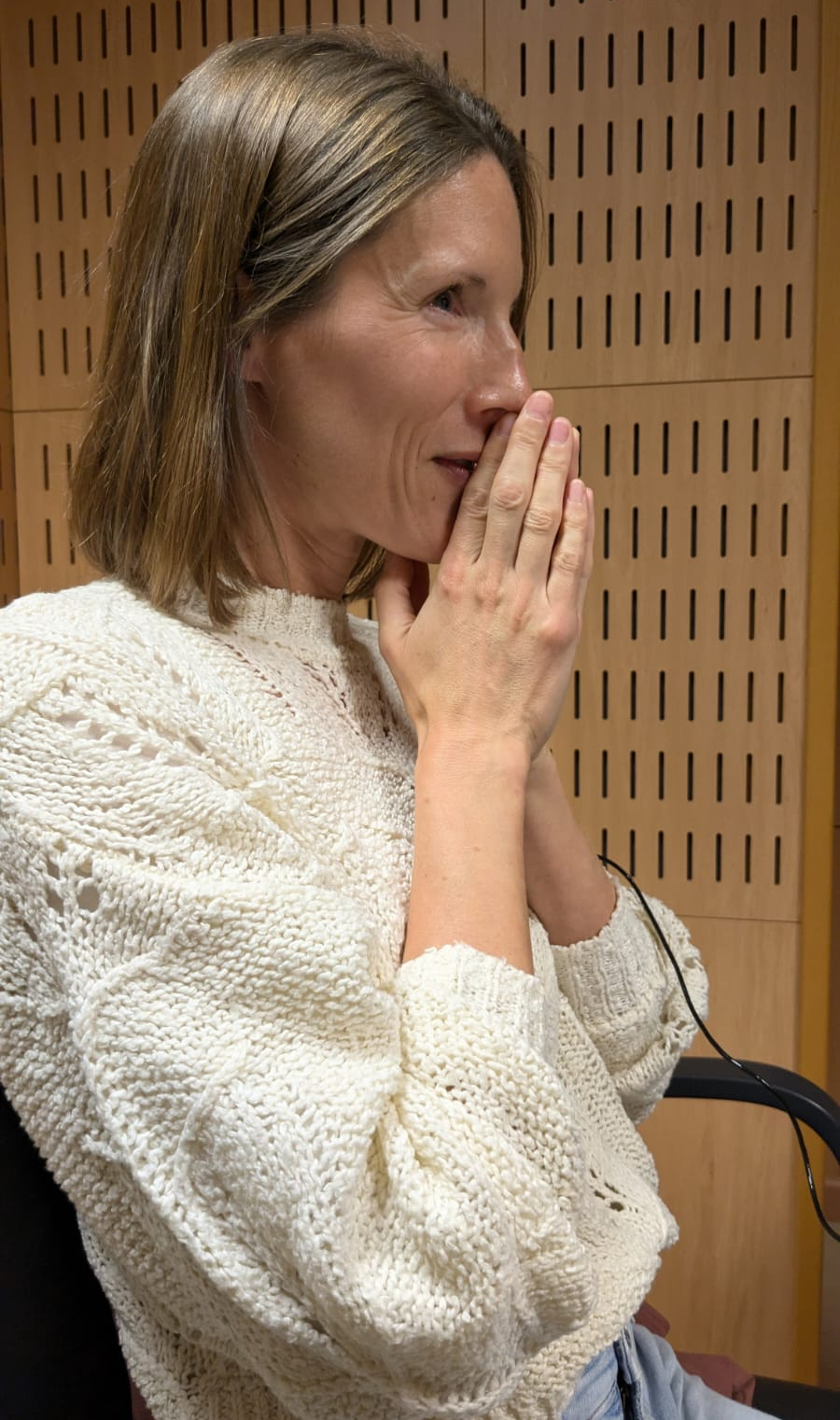 Photo of Carly with her hands together in front of her mouth. Her eyes are full of tears as she hears the beep of the first electrode - hearing in her left ear for the first time in 8 years.